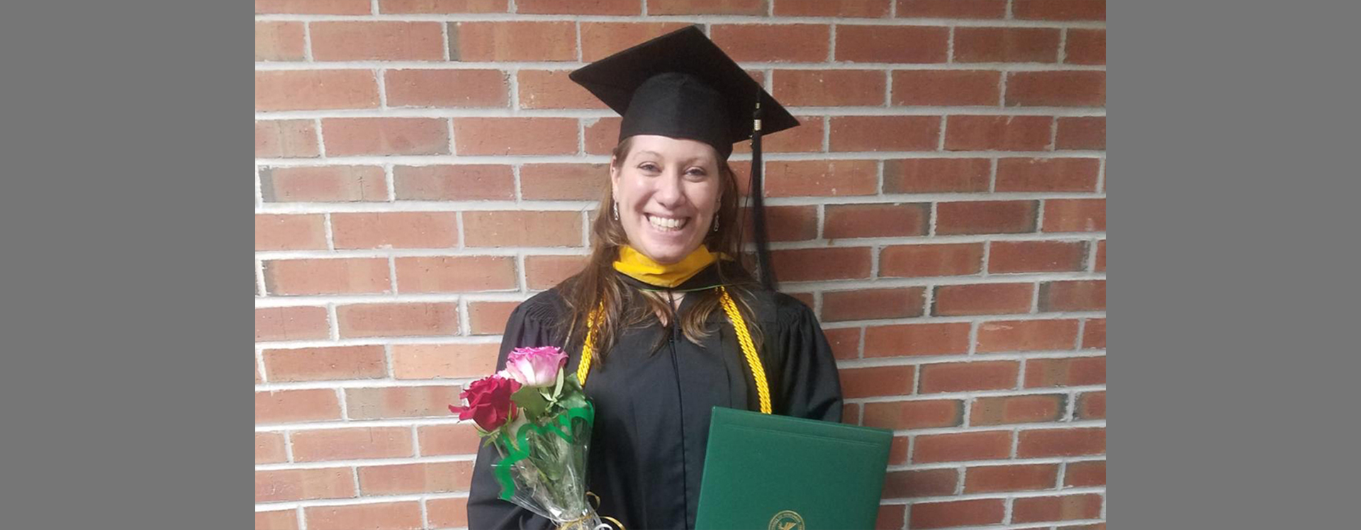 Laura Kuglitsch smiling in her cap and gown at her 2018 master's graduation.